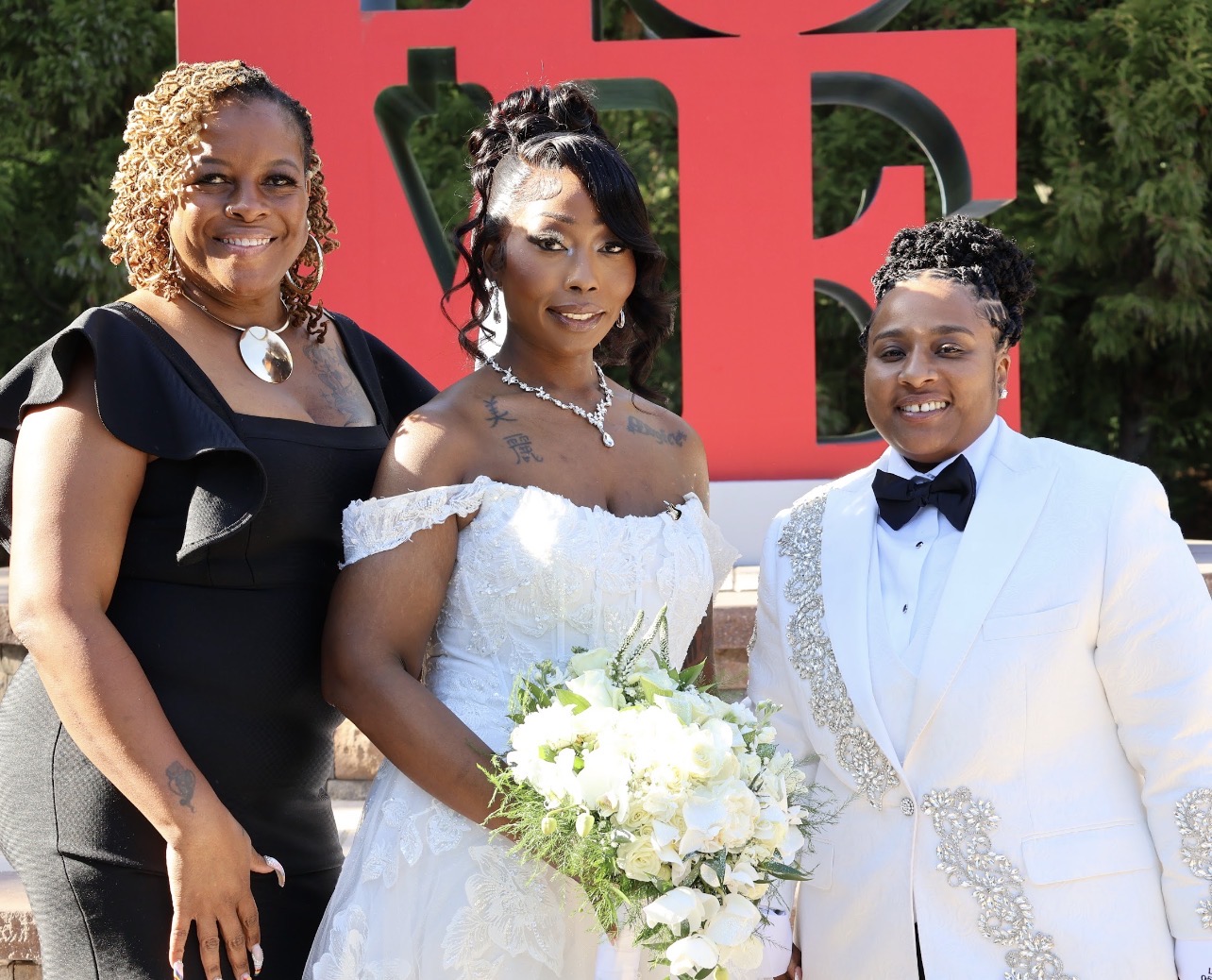 Kesha standing with two brides in front of the LOVE sculpture