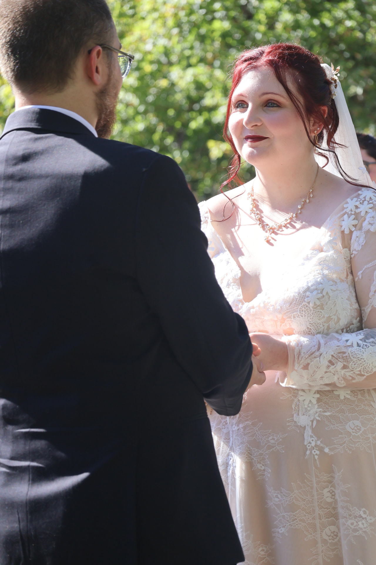 Couple holding hands during an outdoor ceremony in the sunshine